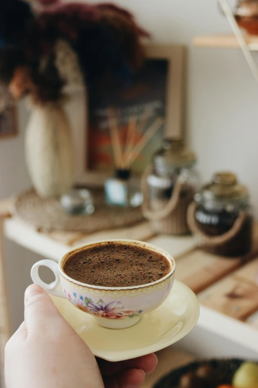 a person holding a cup of coffee in their hand, a picture, by Lucia Peka, hurufiyya, homemade, brown, indoor setting, soup