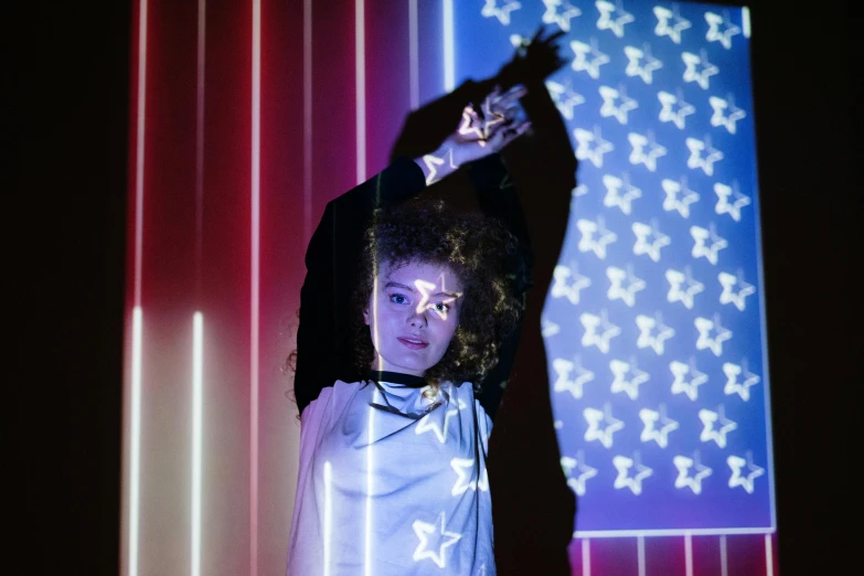 a man standing in front of an american flag, a hologram, by Julia Pishtar, three point lighting bjork, ashteroth, photo from a promo shoot, nightlife