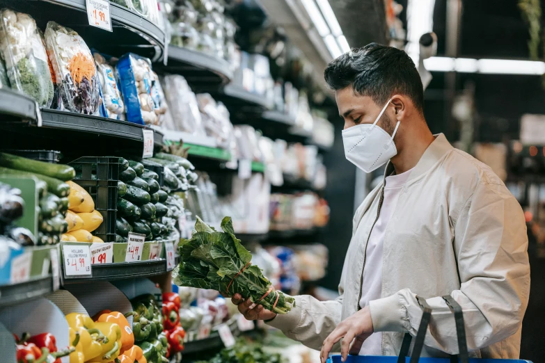 a man wearing a face mask while shopping in a grocery store, by Nicolette Macnamara, pexels, 🦩🪐🐞👩🏻🦳, confident holding vegetables, ash thorp khyzyl saleem, australian