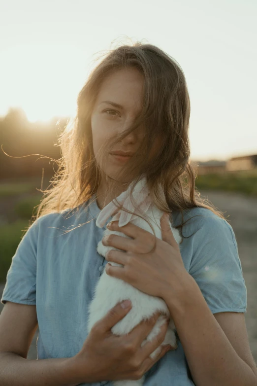 a woman holding a white cat in her arms, unsplash, golden hour cinematic, handsome girl, multiple stories, rabbit