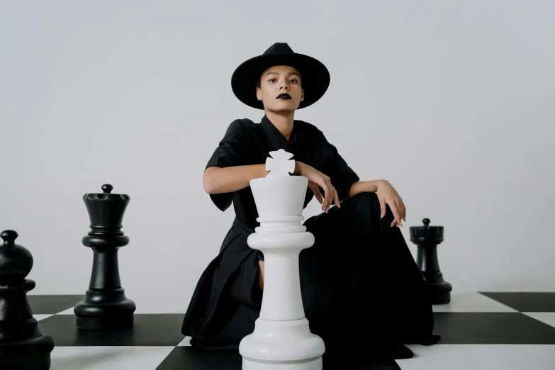 a woman sitting on top of a chess board, an album cover, pexels contest winner, black pointed hat, tessa thompson inspired, formal attire, pose 4 of 1 6