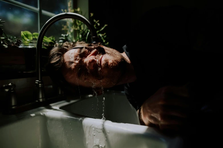 a man drinking water from a faucet in a kitchen sink, inspired by Elsa Bleda, pexels contest winner, renaissance, cream dripping on face, lying down, people drowning, underexposed