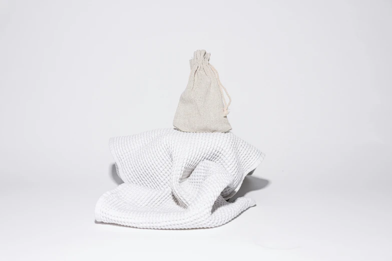 a white towel sitting on top of a white towel, by Alice Mason, pouches, textured base ; product photos, wrapped, objects levitating