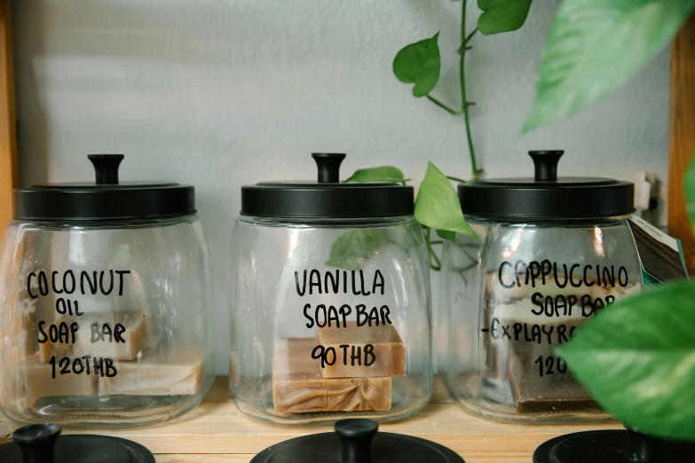 a couple of jars sitting on top of a wooden shelf, labels, in a coffee shop, soap, profile image