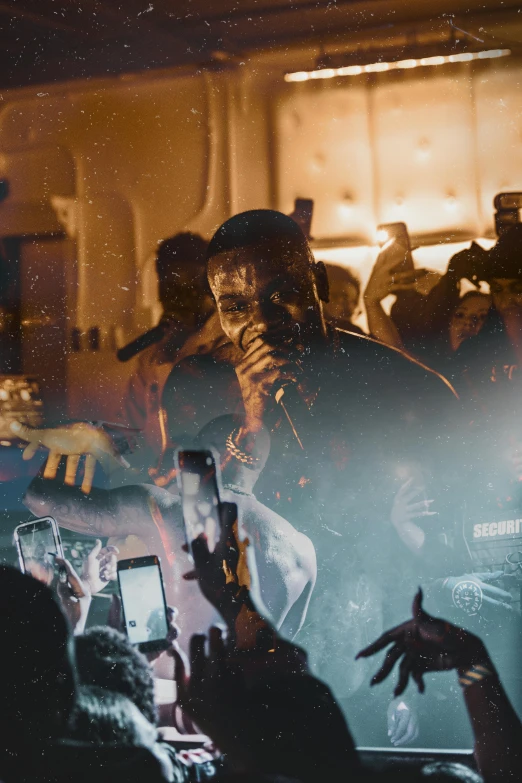 a man holding a microphone in front of a crowd of people, an album cover, pexels, renaissance, gunplay, grime, ( ( theatrical ) ), mid night