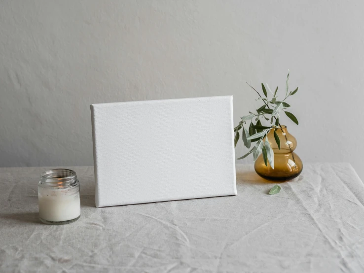 a picture frame sitting on top of a table next to a candle, a minimalist painting, unsplash, made of all white ceramic tiles, on canvas, for displaying recipes, deckle edge