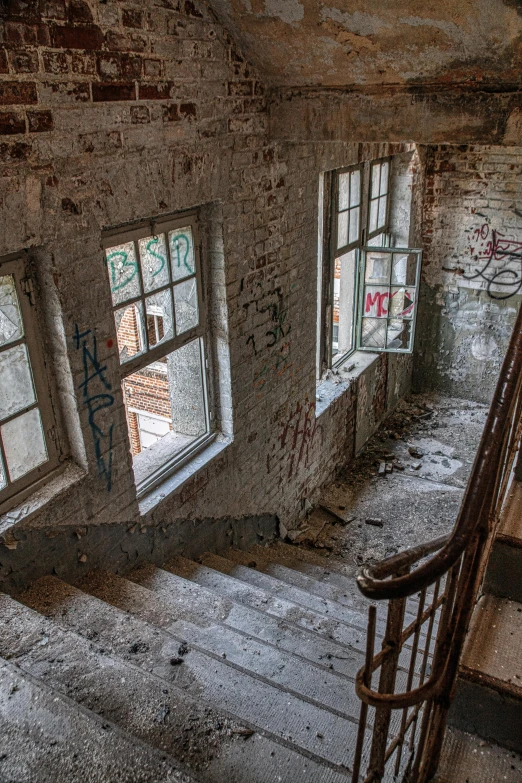 a staircase in an old building with graffiti on the walls, by Sebastian Spreng, pexels contest winner, cracked windows, high view, back rooms, large open windows