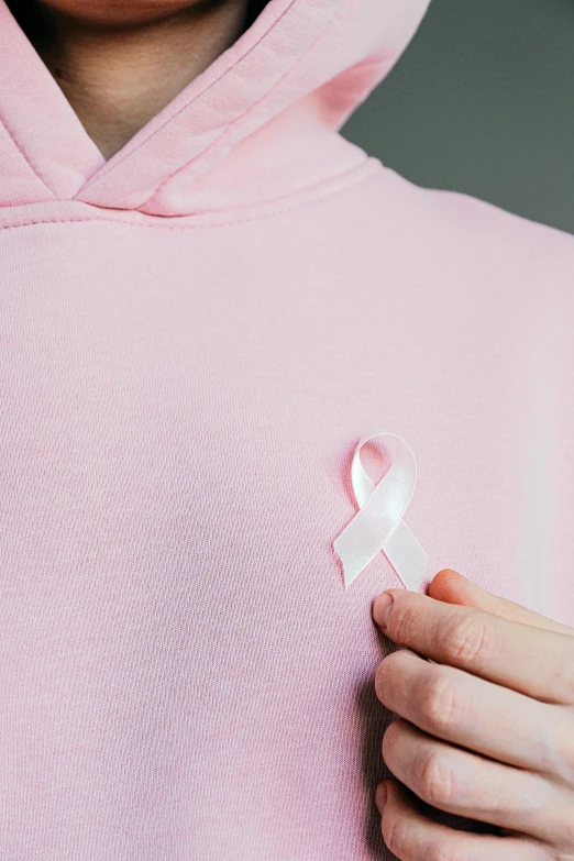 a woman in a pink hoodie with a pink ribbon on her chest, detail shot, photograph credit: ap, ((pink)), promo image