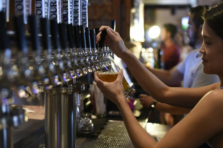 a woman filling up a beer at a bar, by Carey Morris, pexels, multiple stories, lachlan bailey, bottom angle, daily specials