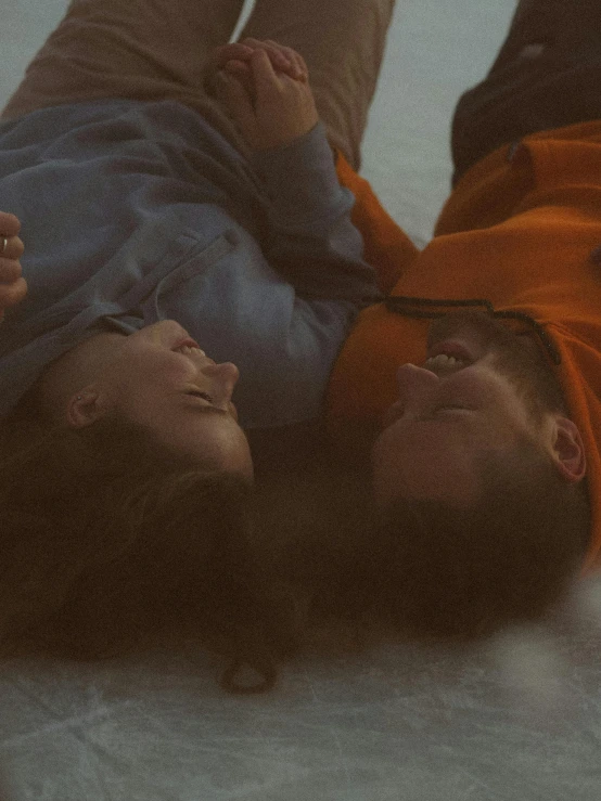 a couple of people laying on top of a snow covered ground, trending on pexels, looking at each other mindlessly, grainy footage, turning her head and smiling, lesbians