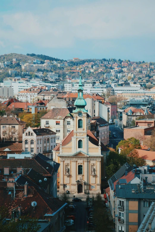 a view of a city from the top of a hill, by Adam Szentpétery, square, full frame image, church in the background, high res 8k