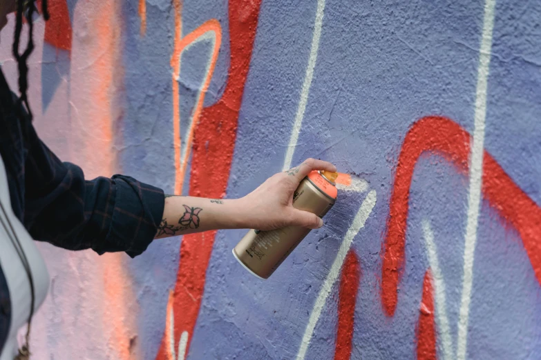 a person spray painting graffiti on a wall, by Mór Than, unsplash, graffiti, gray and orange colours, holding flask in hand, promo image, instagram post