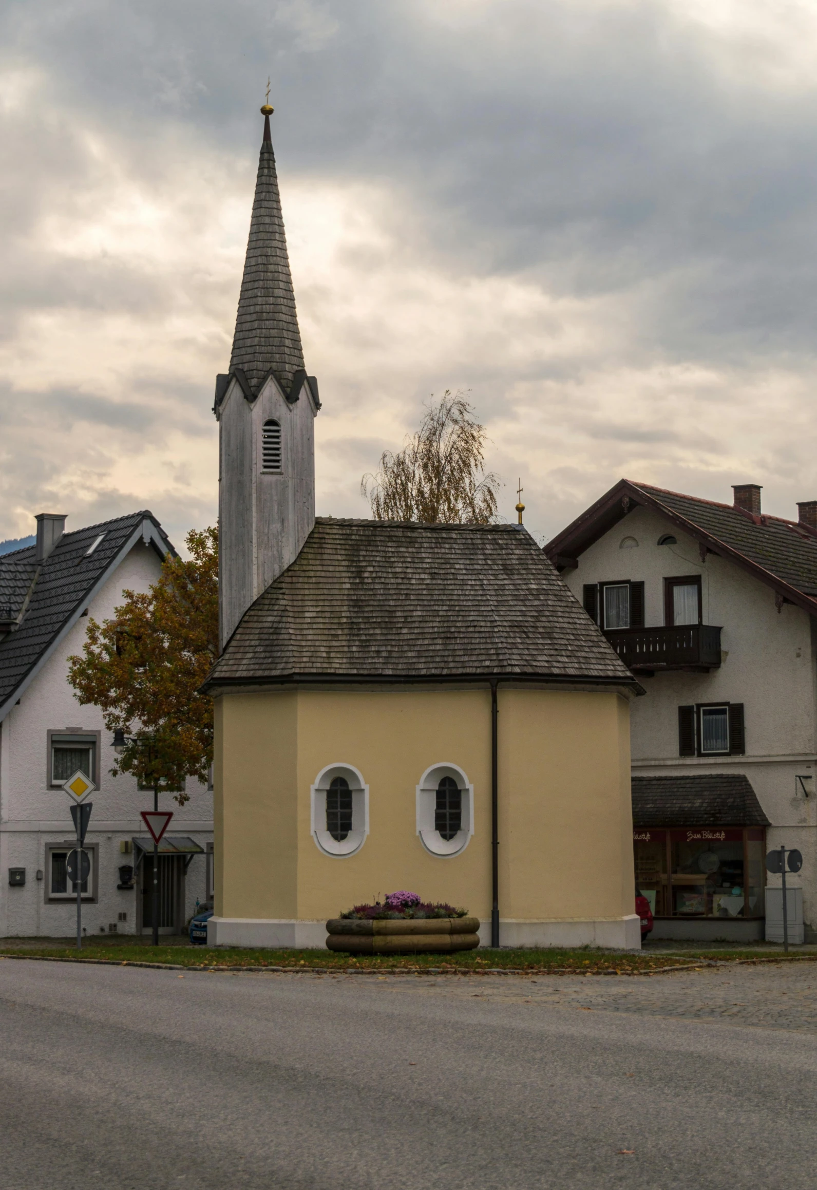 a street with houses and a church in the background, by Karl Gerstner, unsplash, in a square, atlach - nacha, small cottage in the foreground, monument