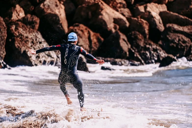 a man riding a wave on top of a surfboard, unsplash, rock pools, ironman, skintight suits, waving