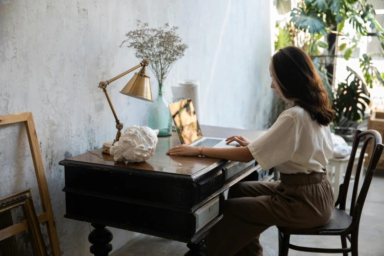 a woman sitting at a desk using a laptop computer, by Julia Pishtar, pexels contest winner, brown and cream color scheme, emerging from her lamp, an asian woman, while marble