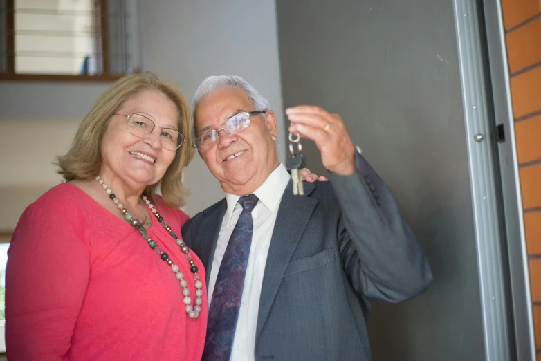 a man and a woman standing next to each other, a photo, pair of keys, older male, te pae, carlos huante