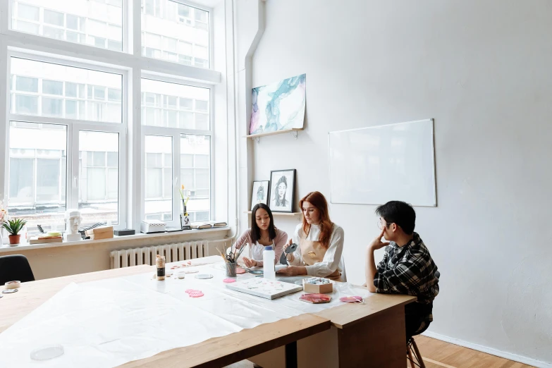 a group of people sitting around a wooden table, pexels contest winner, arbeitsrat für kunst, whiteboards, origami studio 3 design, white room, gemma chen