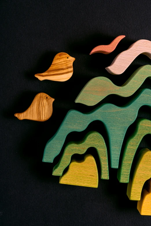 a group of wooden toys sitting on top of a table, inspired by Eyvind Earle, trending on unsplash, ecological art, flowing hills, colorful birds, detail shot, pastel palette silhouette