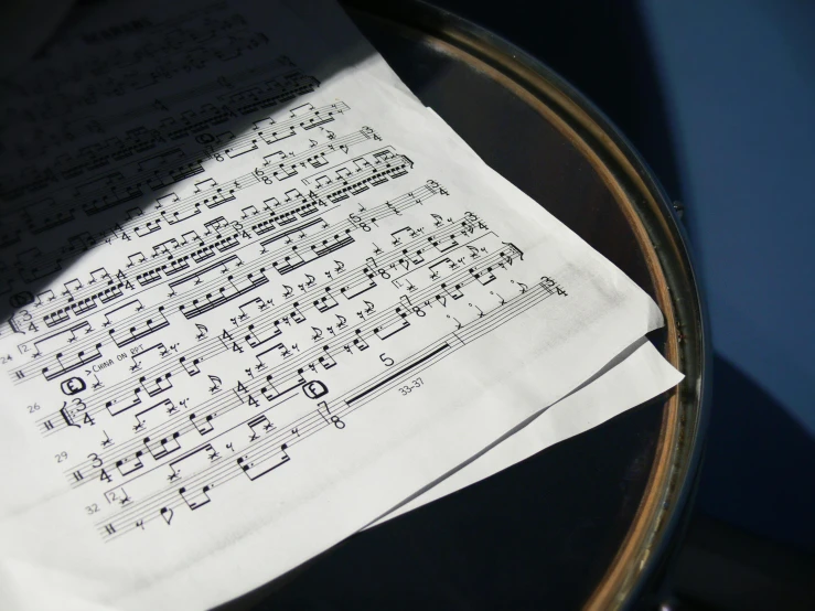 a sheet of music sitting on top of a drum, pexels, private press, multiple stories, next to window, close up details, rim lit