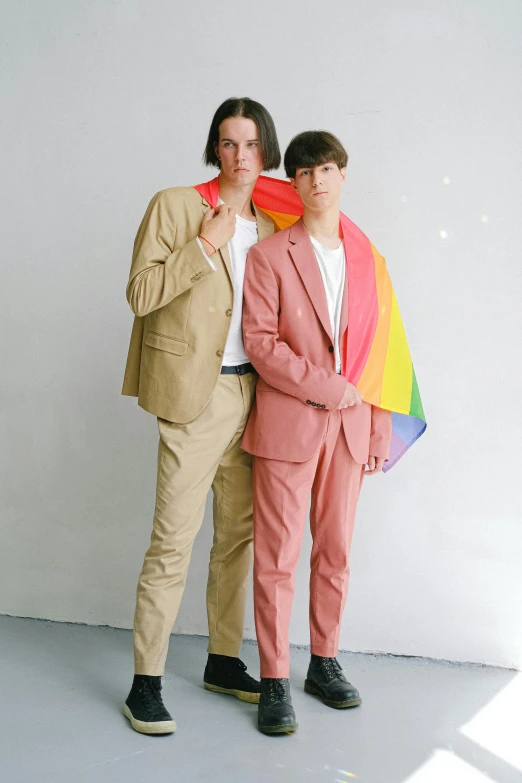 a couple of men standing next to each other, an album cover, by Ellen Gallagher, unsplash, bauhaus, wearing a light - pink suit, pride month, declan mckenna, fullbody photo
