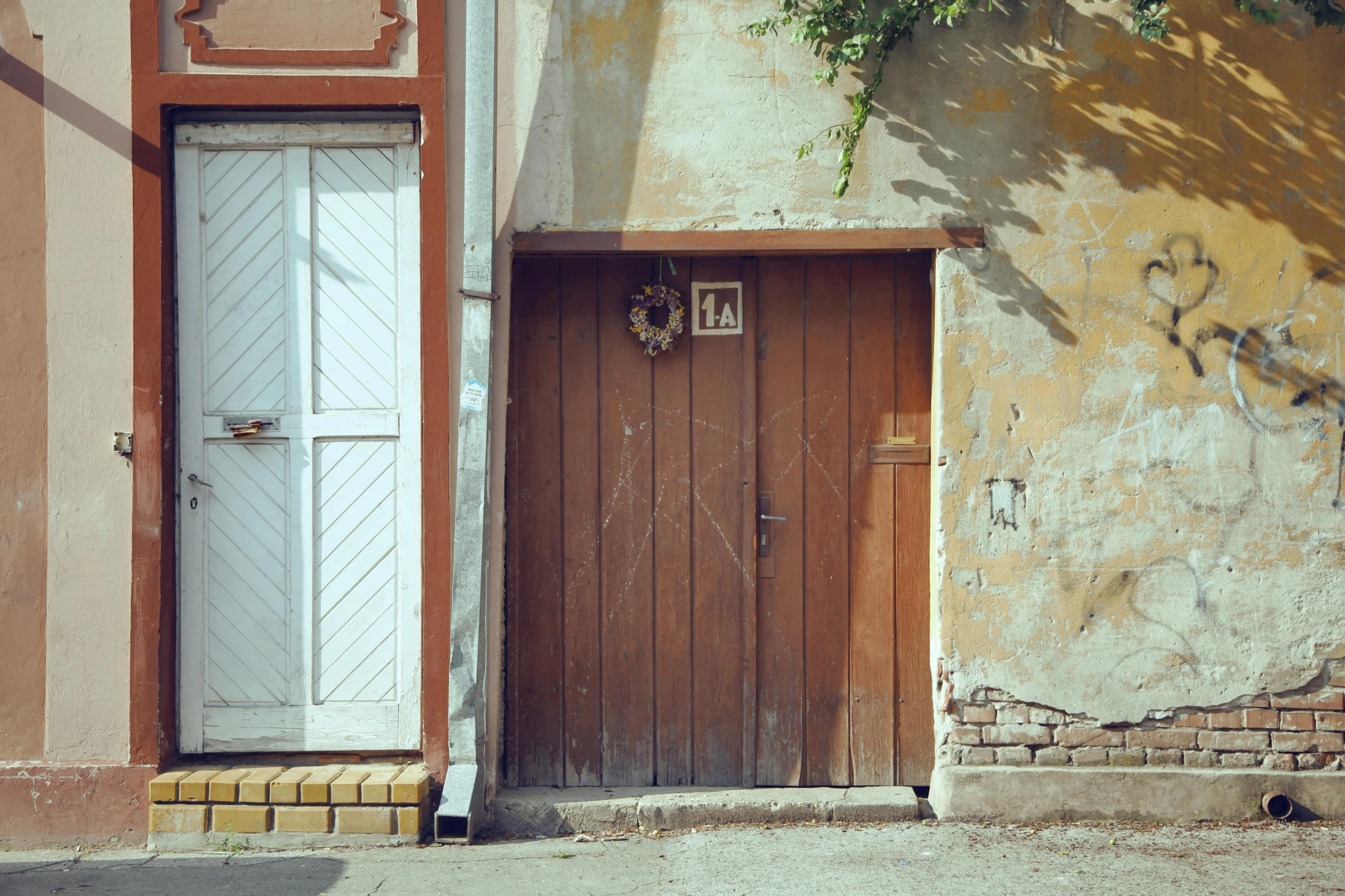 a wooden door sitting on the side of a building, by Attila Meszlenyi, pexels contest winner, sunfaded, dingy city street, miscellaneous objects, medium format. soft light