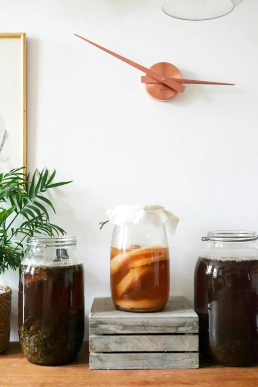 a wooden table topped with jars filled with liquid, ice tea in a mason jar, clocks, dwell, filter