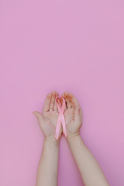 two hands holding a pink ribbon against a pink background, by Carey Morris, pexels contest winner, medical image, instagram post, portrait of small, mew