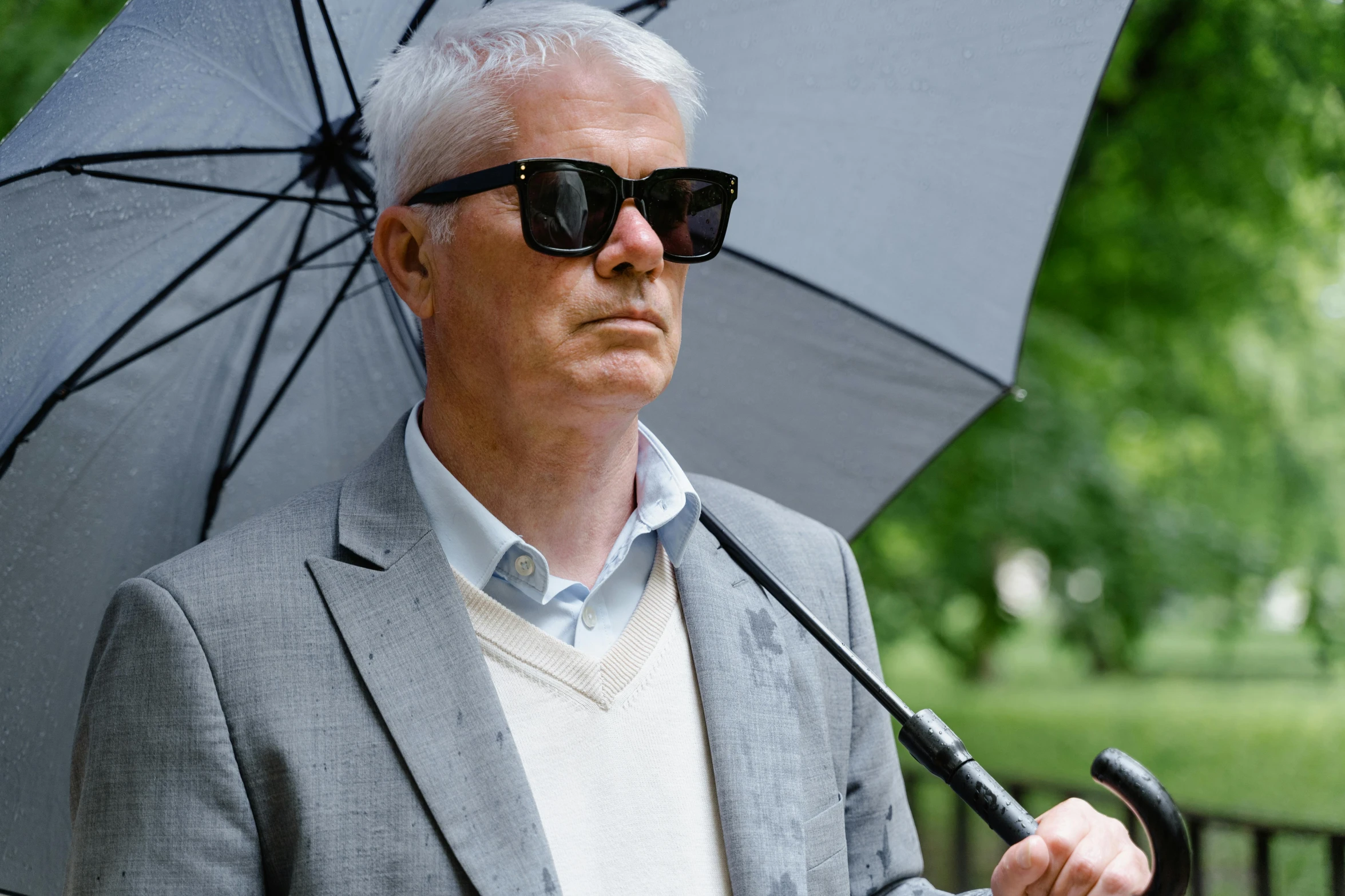 a man in a suit and sunglasses holding an umbrella, by Graham Forsythe, blinding white hair, petri rahkola, journalistic photo, profile image