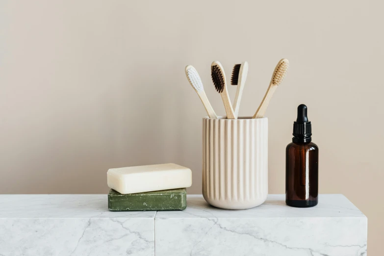 a couple of toothbrushes sitting on top of a counter, a still life, trending on pexels, minimalism, carved soap, apothecary, on a pale background, sustainable