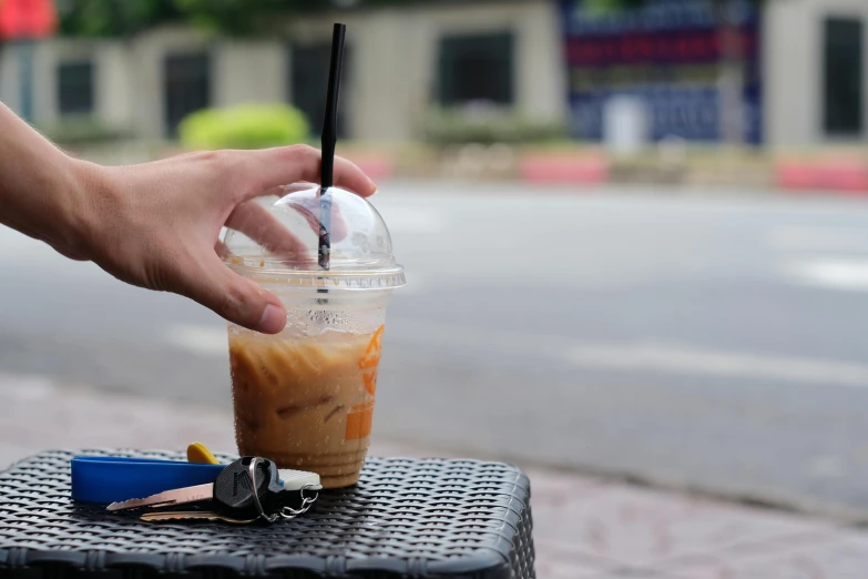 a person taking a drink out of a plastic cup, ice coffee, background image, square, thumbnail