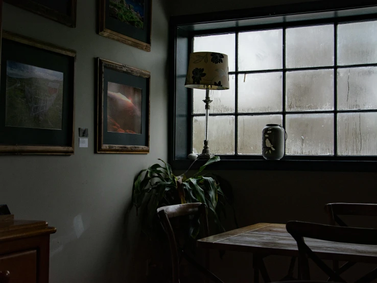 a table and chairs in front of a window, a portrait, unsplash, tonalism, rainstorm, cafe lighting, closed limbo room, vignette of windowsill