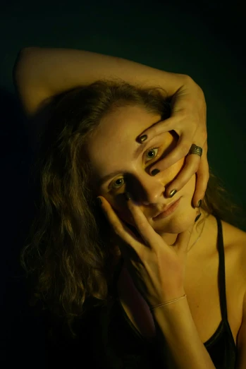 a woman covering her face with her hands, inspired by Elsa Bleda, photorealism, with haunted eyes and curly hair, taken in 2022, dramatic smiling pose, low - lighting