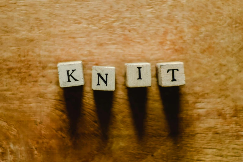 a wooden block with the word knit written on it, pexels contest winner, kinetic art, knights, kit, indie