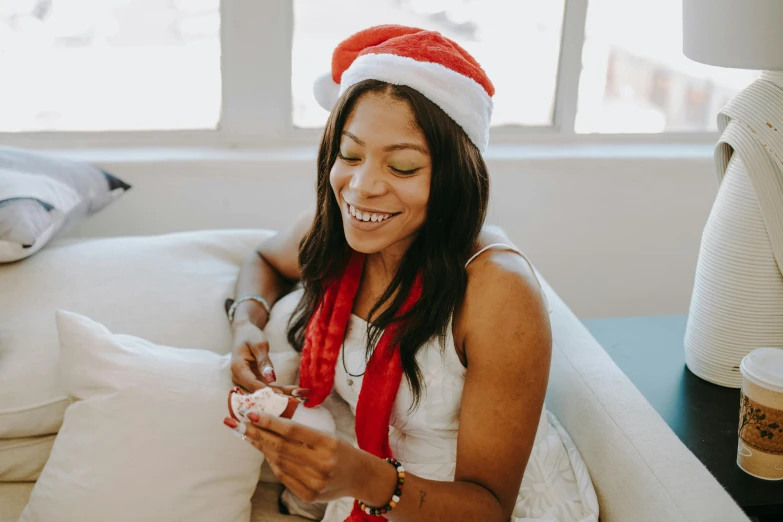 a woman in a santa hat sitting on a couch, pexels contest winner, with brown skin, pleasing, avatar image, profile image