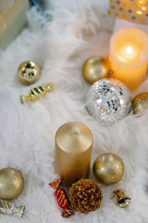 a candle sitting on top of a white fur covered table, golden orbs, a high angle shot, presents, 20k