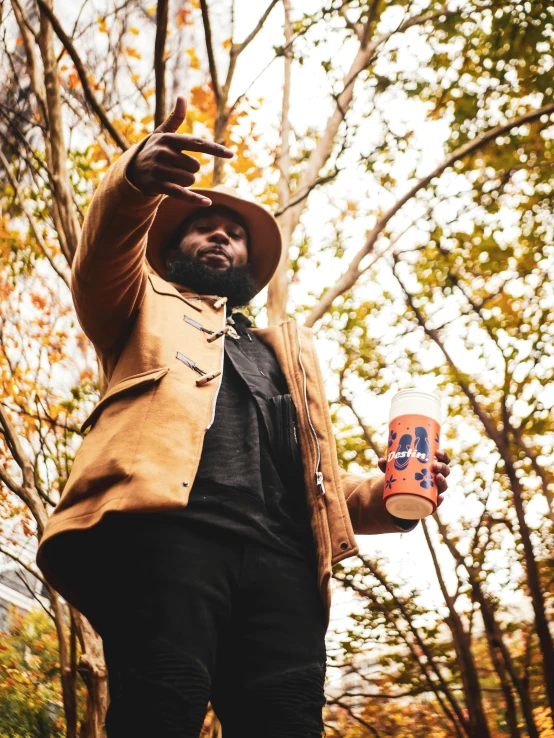 a man standing in the woods holding a skateboard, an album cover, by Nyuju Stumpy Brown, holding a drink, dark blue + dark orange, official store photo, in fall