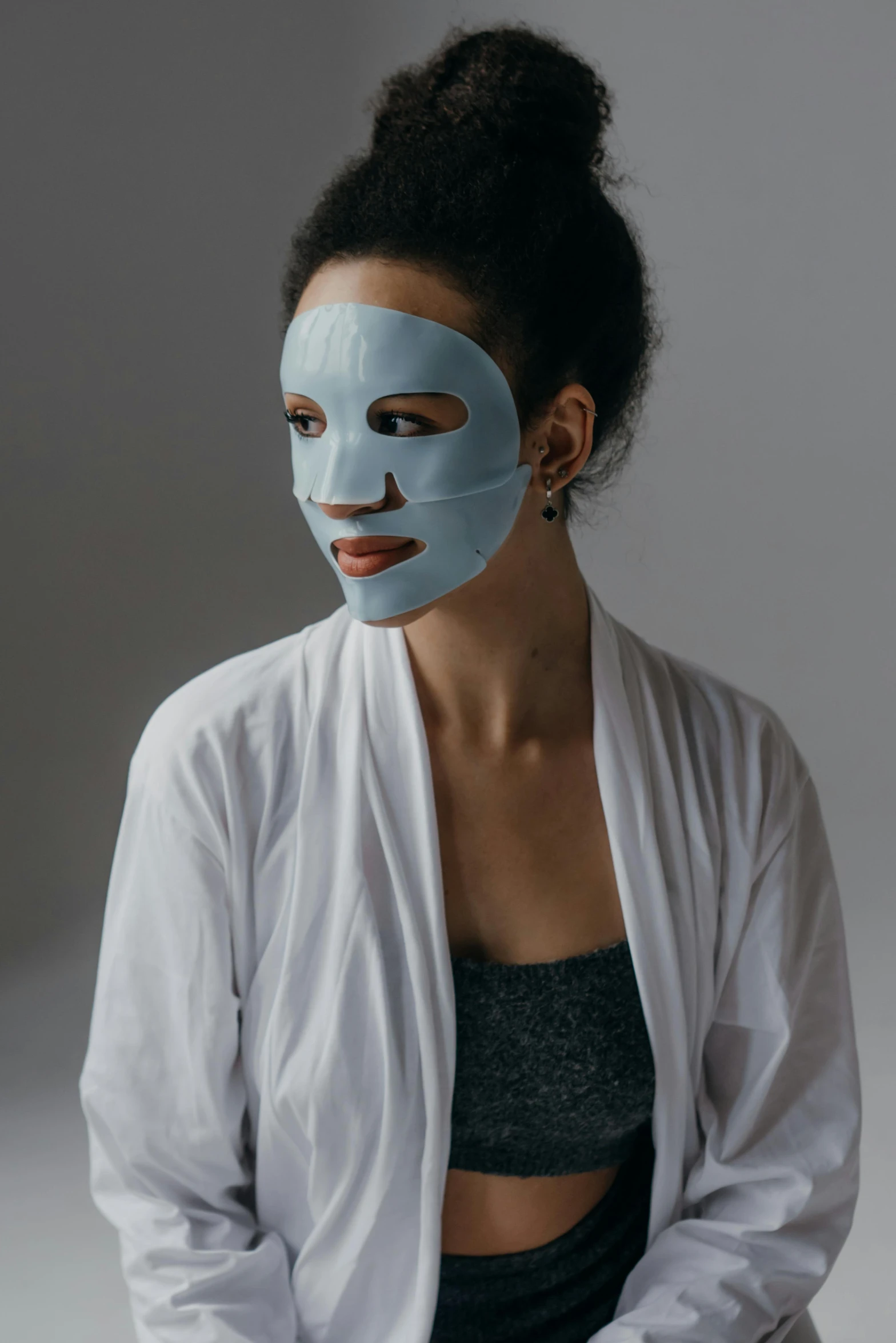 a woman with a blue mask on her face, an album cover, inspired by Marina Abramović, renaissance, on a gray background, healthcare, silicone skin, facemask