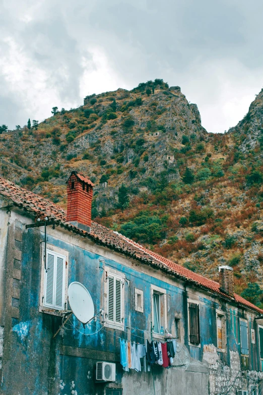 an old building with a mountain in the background, pexels contest winner, prussian blue and venetian red, taras susak, slate, french village exterior