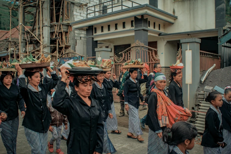 a group of people walking down a street carrying baskets on their heads, by Andrée Ruellan, pexels contest winner, sumatraism, wearing black old dress and hat, square, [ cinematic, funeral