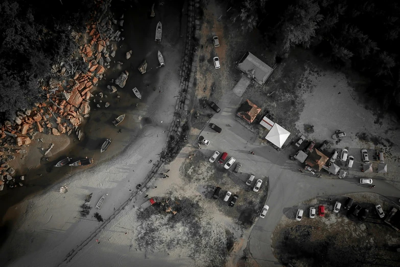 an aerial view of cars parked in a parking lot, by Adam Marczyński, pexels contest winner, auto-destructive art, the village on the cliff, dark and dusty, post apocalyptic theme park, slightly pixelated