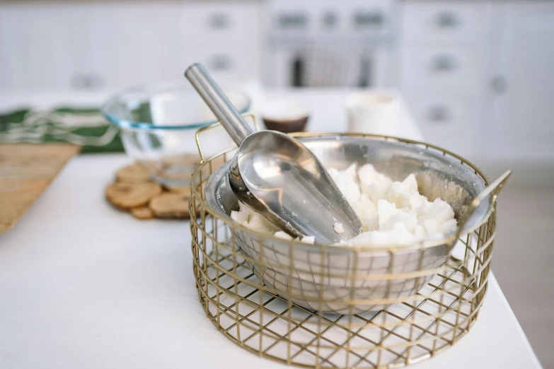 a bowl of rice with a spoon in it, a still life, unsplash, process art, metal kitchen utensils, whipped cream, on a white table, baking cookies