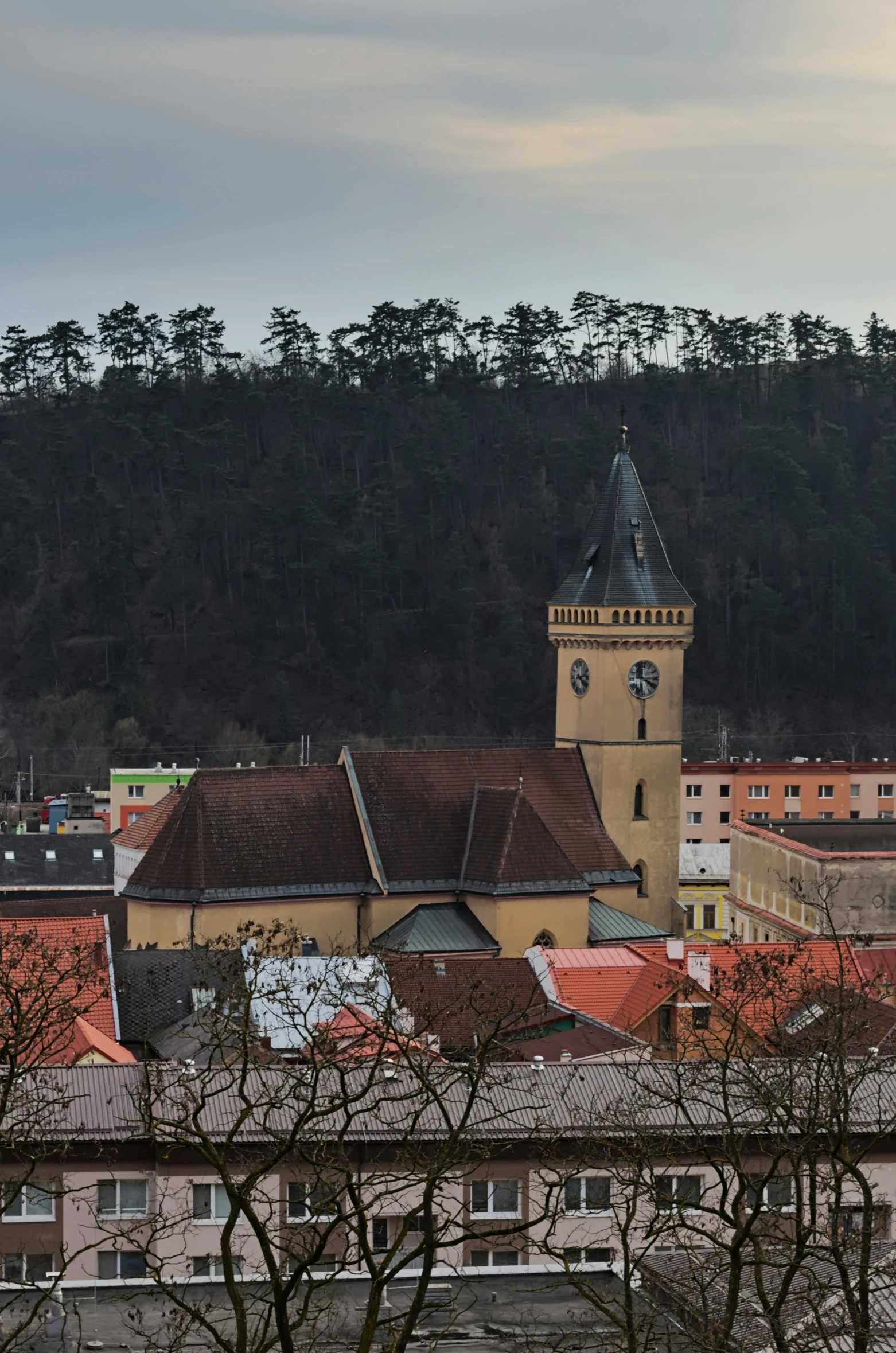 a large clock tower towering over a city, inspired by Ernő Tibor, church in the wood, panoramic shot, square, tiled roofs