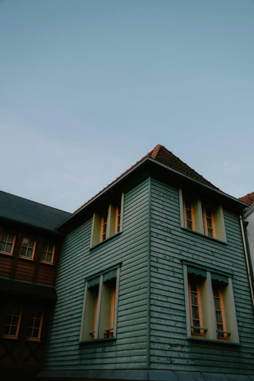 a couple of buildings that are next to each other, by Tobias Stimmer, unsplash, arts and crafts movement, wooden house, muted green, low quality photo, late summer evening