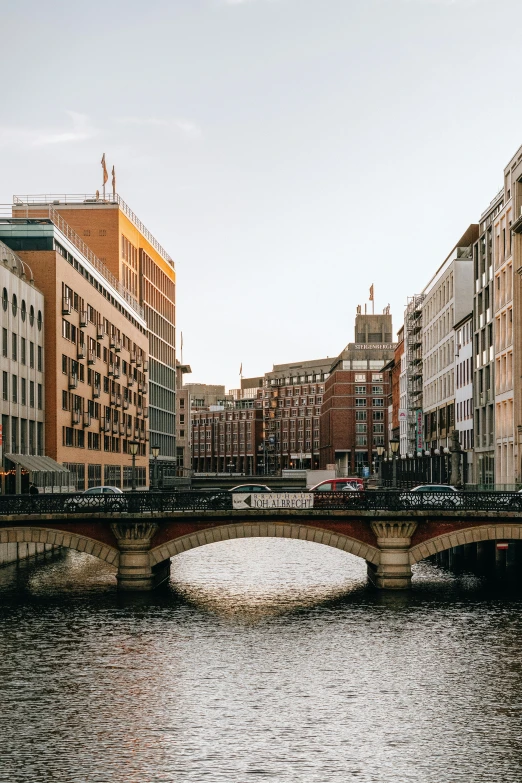 a bridge over a body of water next to tall buildings, by Sebastian Spreng, trending on unsplash, swedish houses, hannover, river flowing through a wall, nice afternoon lighting