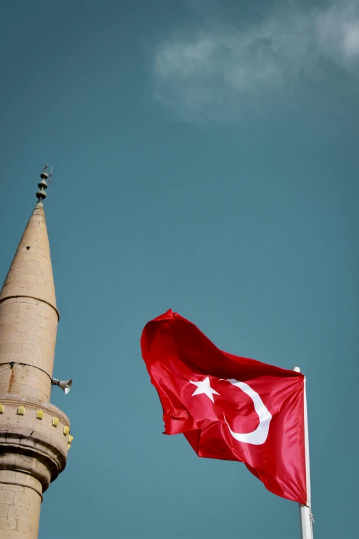 a red and white flag flying next to a tall tower, hurufiyya, lead - covered spire, 2 5 6 x 2 5 6, conde nast traveler photo, turkey