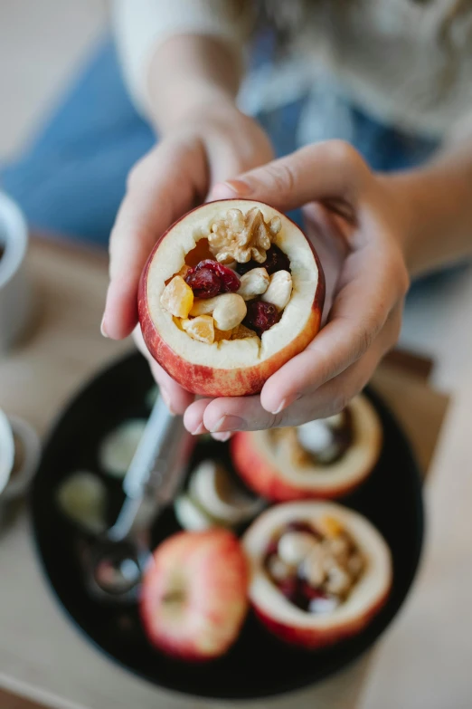 a close up of a person holding an apple, bowl filled with food, carving, breakfast, stuffed