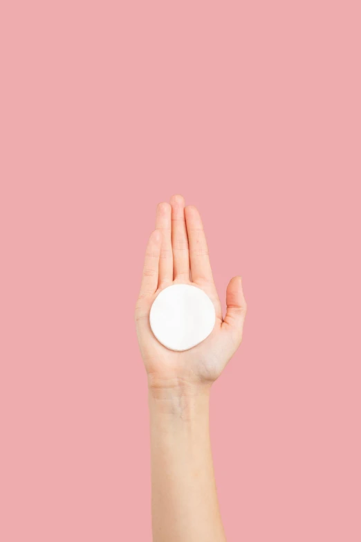 a hand holding a white pill on a pink background, by Anita Malfatti, aestheticism, circle face, powder, on a white background, uploaded