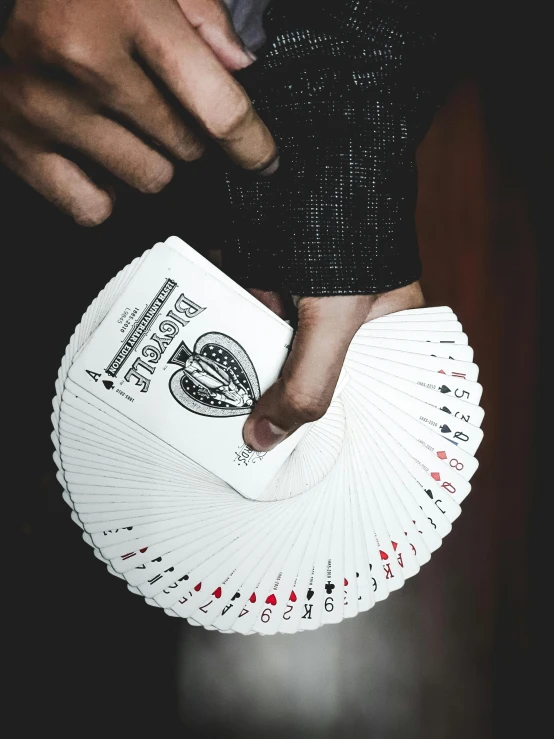 a person holding a deck of playing cards, by Robbie Trevino, teaser, up close image