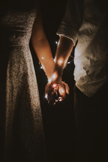a couple holding hands in the dark, pexels, fairy lights, lightly dressed, instagram post, vintage photo