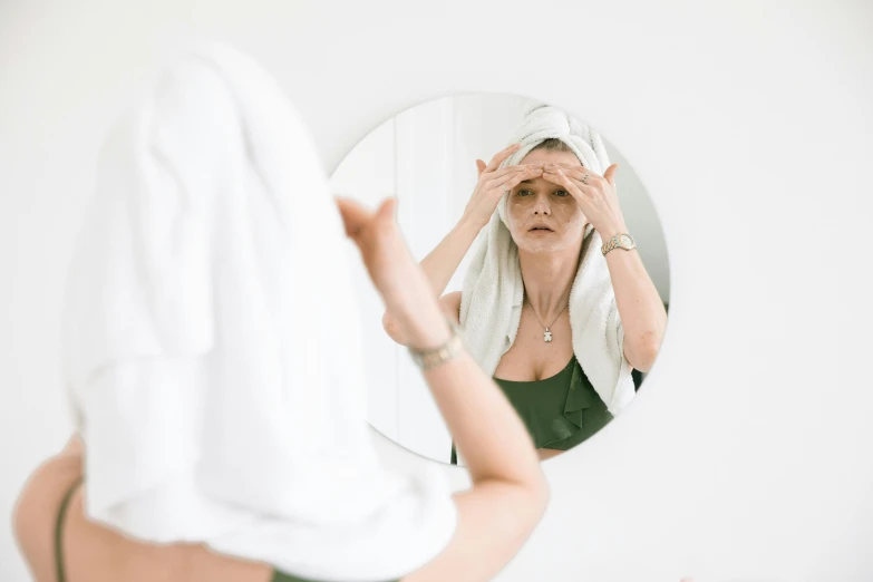 a woman that is standing in front of a mirror, a photo, trending on pexels, wet eye in forehead, photoshoot for skincare brand, wrinkles and muscle tissues, hat covering eyes